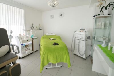 Bright and cozy clinic room featuring a comfortable treatment bed and modern equipment.