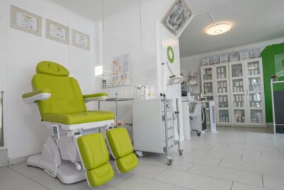 Professional equipment in doctor office with couch for medical treatment procedures behind protective screen