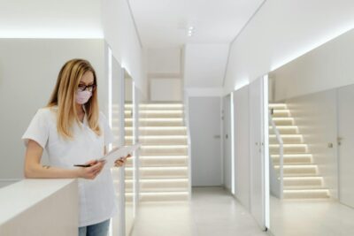 A woman in scrubs and face mask working in a bright, modern medical clinic.