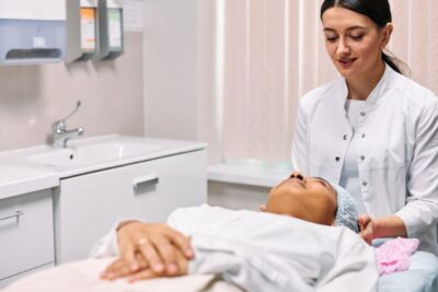 A beautician providing skincare treatment to a woman in a clinic setting, focusing on care and relaxation.