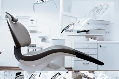 A modern dental clinic interior showcasing a dental chair and equipment in a clean, clinical setting.
